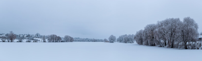 Panorama of winter landscape. Trees are covered with snow and frost.