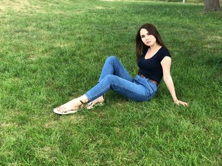 Beautiful portrait of thinking young woman with long brown hair on the grass background. Ukrainian girl