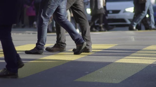 Slow motion shot of groups of people crossing a busy shopping street in Z&uuml;rich city center in sunny winter at daytime.