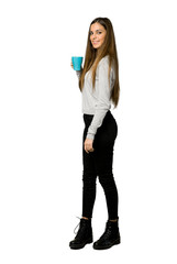Full-length shot of young girl holding a hot cup of coffee on isolated white background