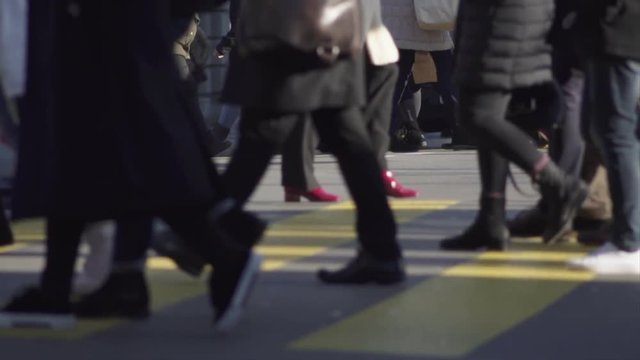Slow motion shot of many people carrying shopping bags while crossing a busy main street in Z&uuml;rich city center on a cold and sunny winters day.