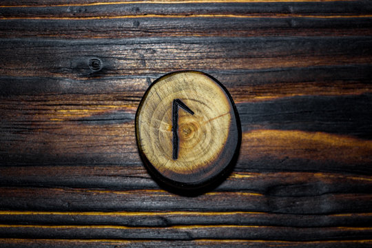 Rune Laguz (Laukaz, Lagu) carved from wood on a wooden background - Elder Futhark