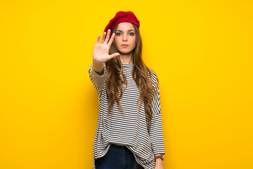 Girl with french style over yellow wall making stop gesture denying a situation that thinks wrong