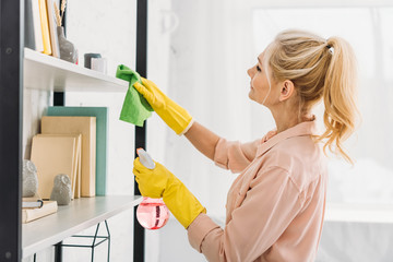 Senior woman with pony tail cleaning shelves with rag