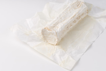 Stick of a goat cheese on paper on  the white background.