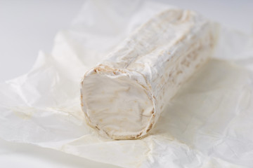 Stick of a goat cheese on paper on  the white background.
