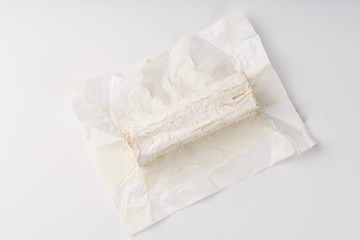 Stick of a goat cheese on paper on  the white background.