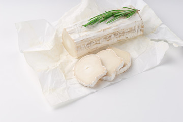 Stick of a goat cheese on paper on  the white background.