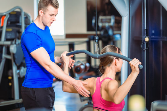 Handsome personal trainer guiding a beautiful woman at a modern fitness club