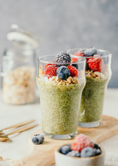 Chia pudding with matcha tea, organic granola, frozen berries in glasses. The concept of healthy vegan food.