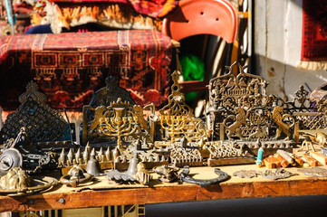 Different Hannukah menora and other candlesticks at the flea market in Jaffa (Israel). Judaica background. Selective focus and shallow depth of field. 