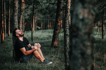 Young depressed man sitting alone in the forest