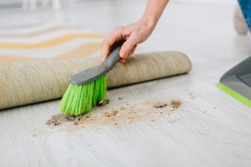 Cropped shot of woman sweeping floor with green brush
