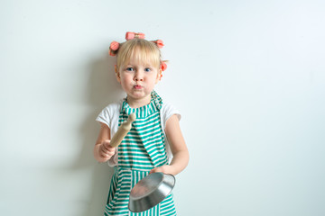 toddler in role of crasy andgry housewife with frying pan and pink curlers
