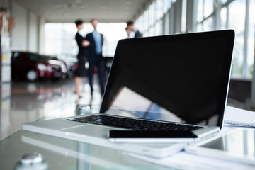 Closeup photo of laptop computer with open top and business people in background