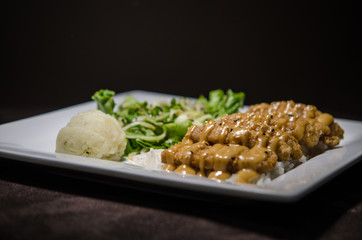 Japanese pan fry with salad and rice in black background.