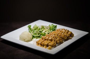 Japanese pan fry with salad and rice in black background.