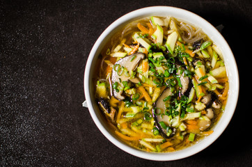 Shiitake soup in white bowl in black background