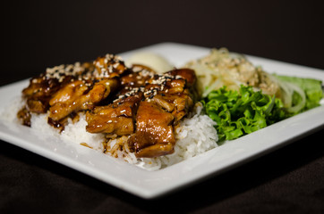 Teriyaki chicken in white plate and dark back ground.