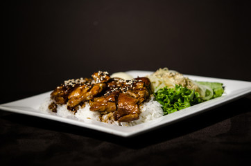 Teriyaki chicken in white plate and dark back ground.