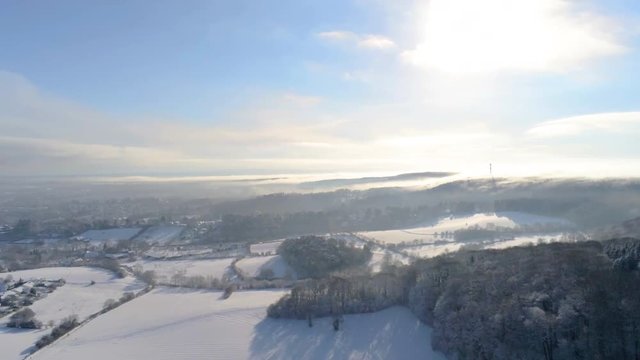 Panning motion over snow covered winter wonderland in German Eifel close to Aachen with drone over meadows and forrest