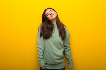 Teenager girl with green sweatshirt on yellow background happy and smiling