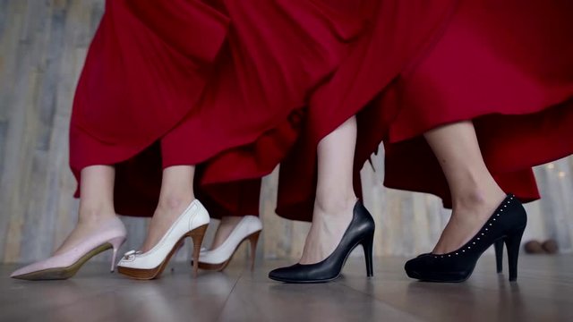 legs of four girls in high heels, red dresses develop