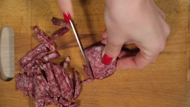 Slicing sausage on a cutting board. Beef sausage. Cut with a kitchen knife.