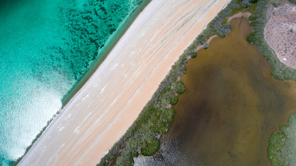 Sand, rock, and sea patterns on cristal clear waters.