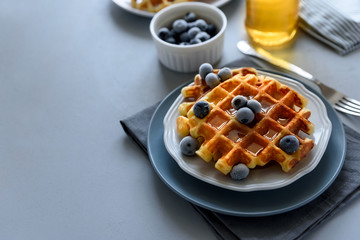 Belgian waffles with blueberries and honey on gray wooden background. Homemade healthy breakfast. Selective focus