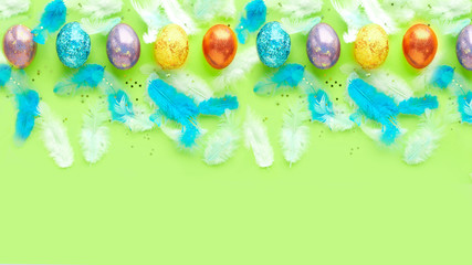 square of easter eggs on a green background. scattered blue feathers. banner for text