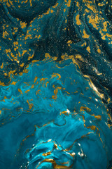 Abstract paint texture art. Natural luxury. Blue paint with gold glitter powder. Marble background.
