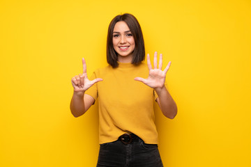 Young woman over yellow wall counting seven with fingers