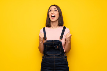 Young woman over yellow wall shouting to the front with mouth wide open