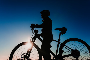 Obraz premium silhouette of a Cyclist Riding the Bike Down Rocky Hill at Sunset. Extreme Sport Concept.