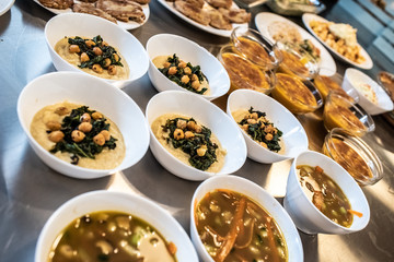 Group of plates with soups of various types in hot bowls.