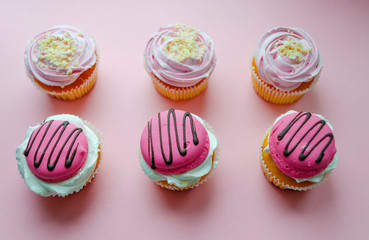 pink cream cupcakes and macaroon on pink background