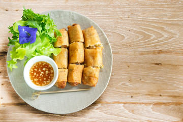 A plate of deep fried spring rolls with sweet chili dip sauce.