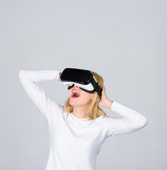 Amazed young woman touching the air during the VR experience. Portrait of young woman wearing VR goggles, experiencing virtual reality using 3d headset. Funny young woman with VR.