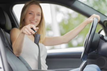 Naklejka premium young woman sitting in new car showing car keys