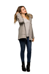 A full-length shot of a Teenager girl with coat thinking an idea while scratching head on isolated white background