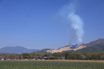 山の斜面から立ち上る野焼きの煙