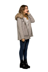 A full-length shot of a Teenager girl with coat keeping a conversation with the mobile phone on isolated white background