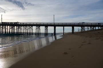 The pier at NEwport Beach in California with silhouettes of people enjoying their time at the beach