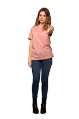 A full-length shot of a Teenager girl with pink sweater inviting to come with hand. Happy that you came on isolated white background