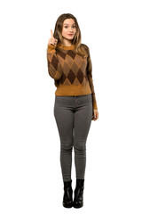 A full-length shot of a Teenager girl with brown sweater thinking an idea pointing the finger up over isolated white background