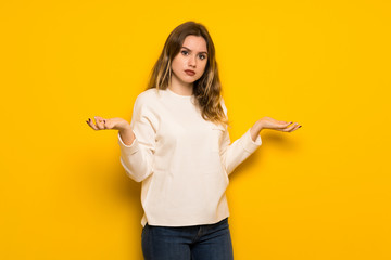 Teenager girl over yellow wall unhappy and frustrated with something because not understand something