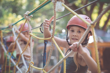little brother and sister make climbing in the adventure park.
