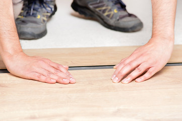 hands laying yellow laminate flooring