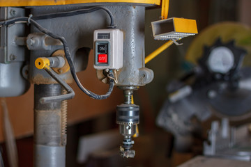 The power buttons of the drilling bench press in the carpenter workshop interior